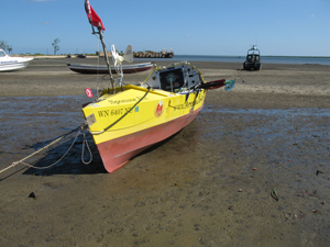 Image: Boat near maritime police building at low tide. Tugboats are resting on the mud in the distance.